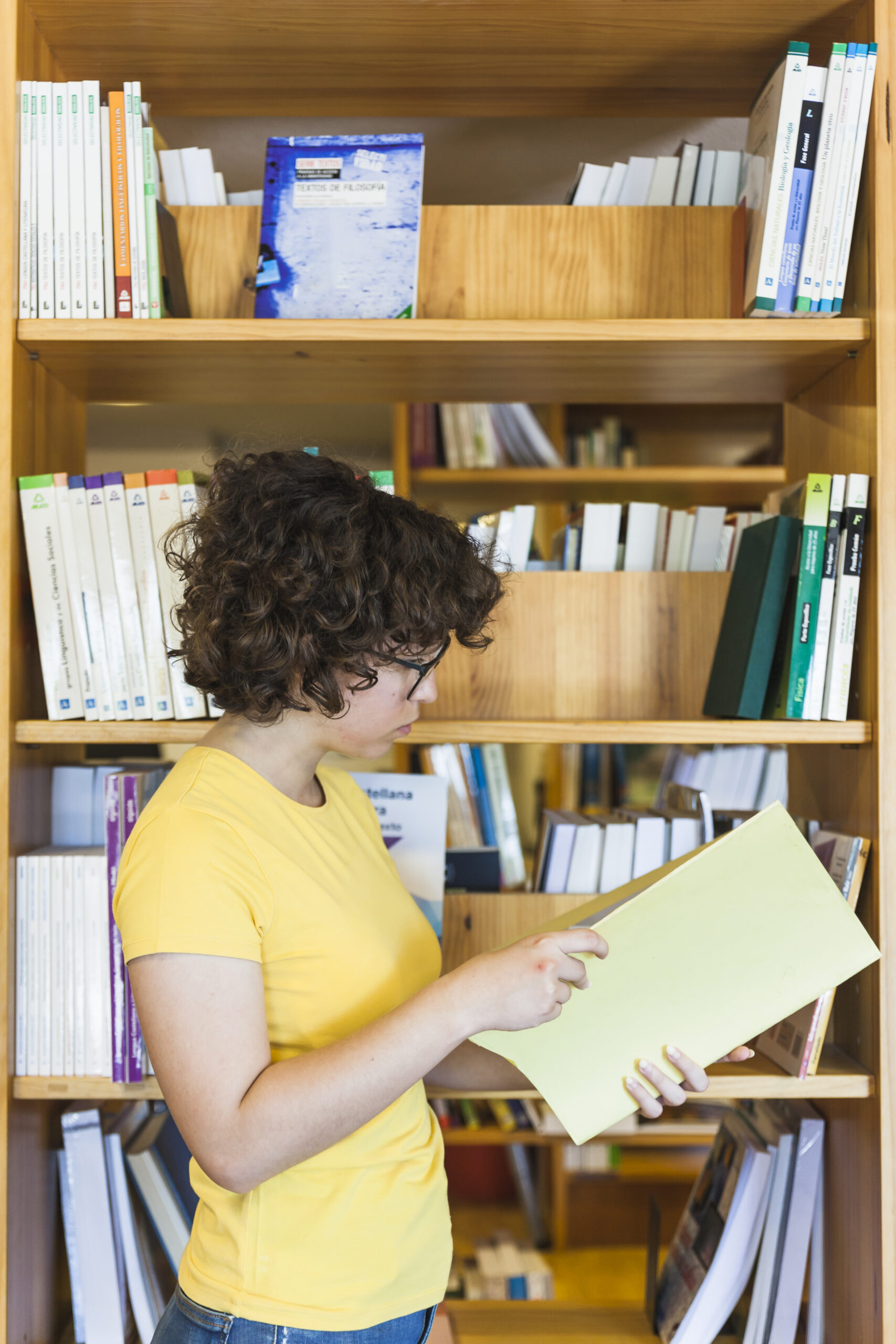 smart-teen-girl-reading-near-bookcase